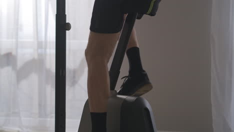 legs-of-slender-aged-man-training-on-stationary-bicycle-in-room-closeup-view-losing-weight-and-keeping-good-physical-condition-in-middle-age